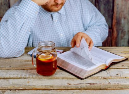 man sitting at a table reading the Bible