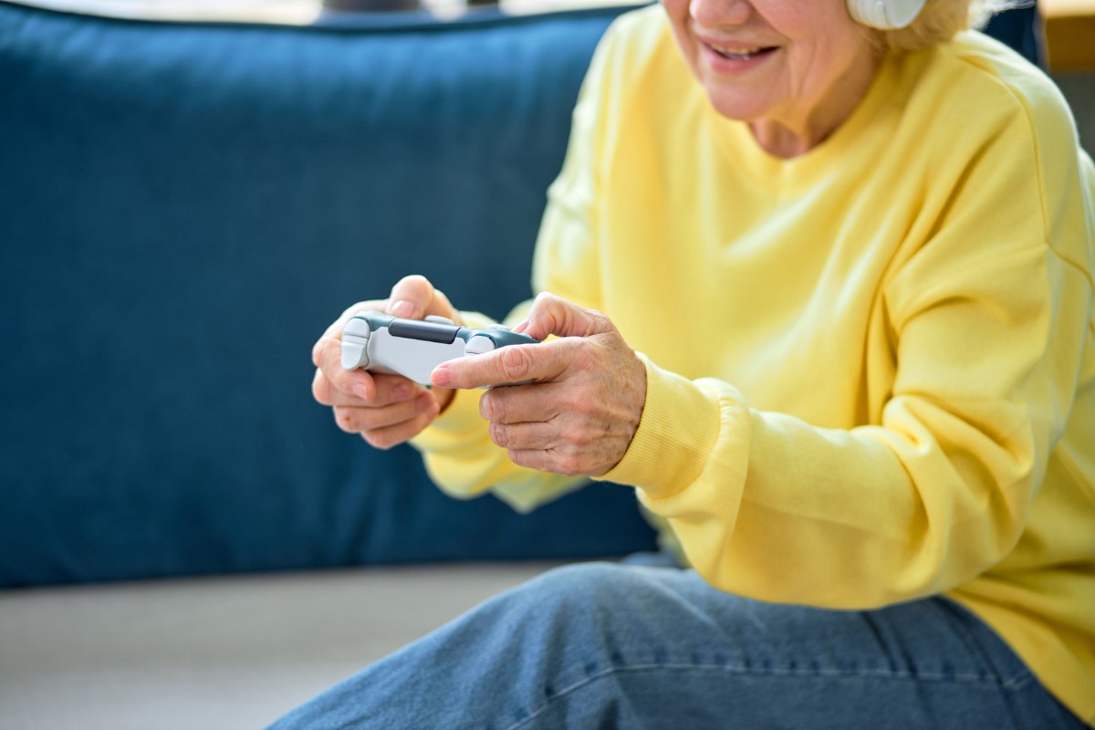 cropped smiling senior caucasian woman playing video game sitting on the sofa at home