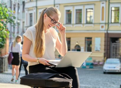 Young businesswoman with laptop outdoors, female looking at computer screen