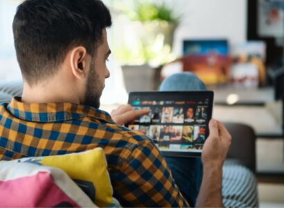 Man Choosing Movie For Streaming On Tablet Computer