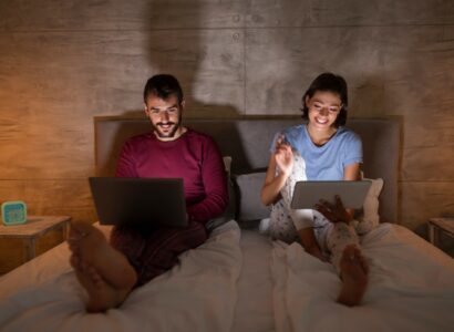 Couple in bed reading and watching TV shows